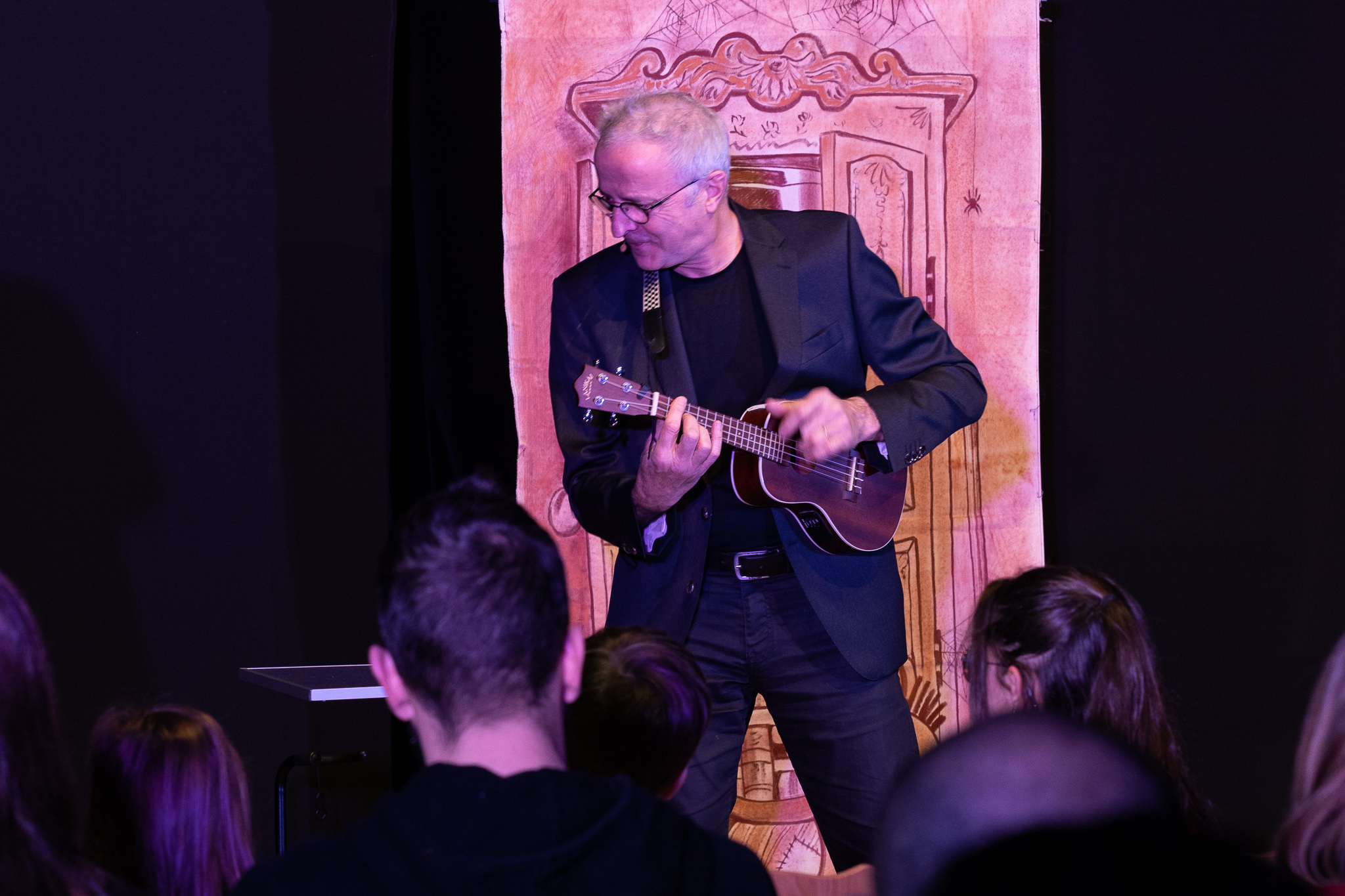 barber using styling spray on young man with black hair, short on sides and long in a quiff on top